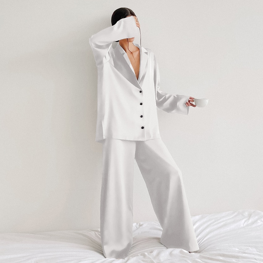 Photo d'une femme portant un pyjama en satin blanc debout sur un lit