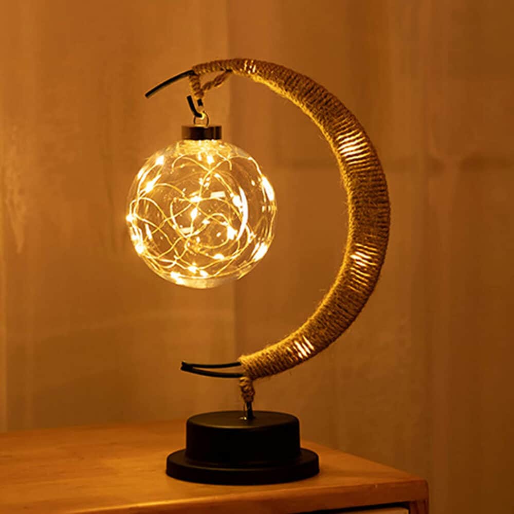 Photo d'une lampe en forme de croissant de lune avec une boule de cristal et une guirlande de LED à l'intérieur.