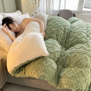 Photo d'une personne dans un lit avec une couverture cocooning verte, en polaire super épaisse et une face effet tricot.