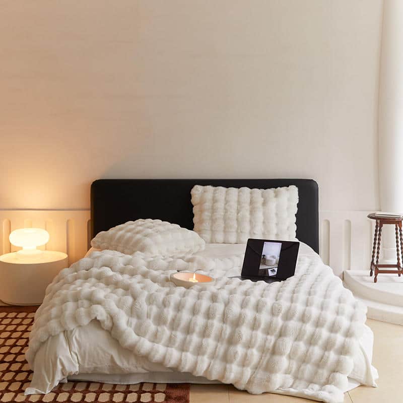 Plaid imitation fourrure blanc posé sur un lit dans une chambre au design minimaliste