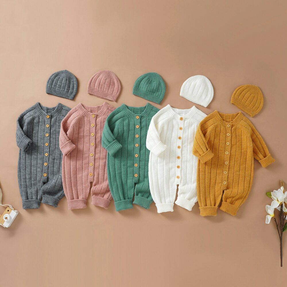 Cinq barboteuse tricotées en laine et leur bonnet sur un fond couleur terracota. Une grise, une rose, une verte , une blanche et une jaune