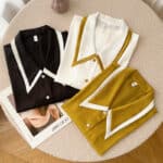 Trois haut de pyjama en satin élégant de styles vintage, pliés et posés sur une table en bois ronde avec un magazine en dessous.