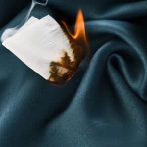 Rideau bleu canard avec un morceau de papier en feu au dessus.