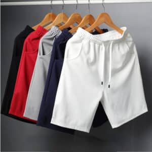 Des shorts de sport pour homme, de différentes couleurs, suspendus à des ceintres.