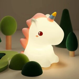Veilleuse lampe en forme de licorne posée sur une table avec des petits arbres
