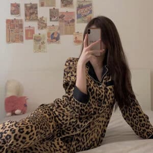 Femme brune sur un lit avec téléphone et pyjama léopard