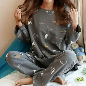 On voit une femme en pyjama deux pièces gris imprimé de chats.
