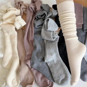 Chaussettes longues d'hiver pour femme de différentes couleurs et une beige porté sur un pied