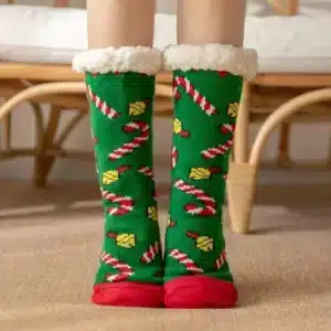 Chaussettes fourrées esprit de Noëlvertes à bout rouge avec des cannes à sucres, porté, devant un fauteuil en rotin.