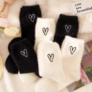 Chaussettes en peluche noires et blanches avec des petits coeurs.