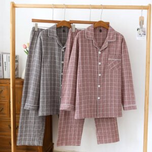 Photo de 2 pyjama à carreaux, un gris et un rose sur des ceintres et un portant en bois.